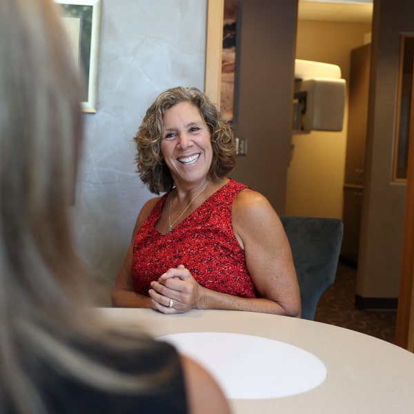 A woman in a red dress is smiling at Issaquah dental practice