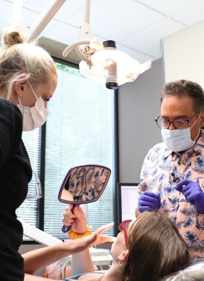 Dr. Ron Sherman and his dental assistant showcasing a new smile to a patient in the dental chair