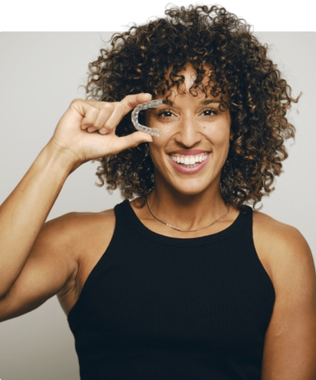 A woman is holding Invisalign and smiling	