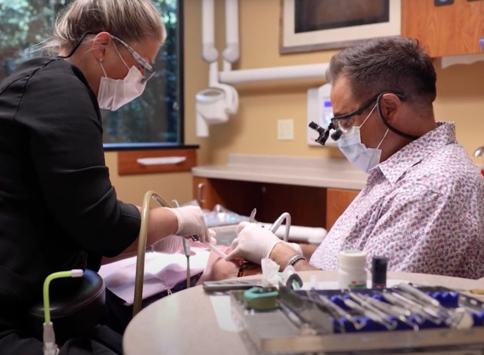 Dr. Ron Sherman with his dental assistant performing dental procedure