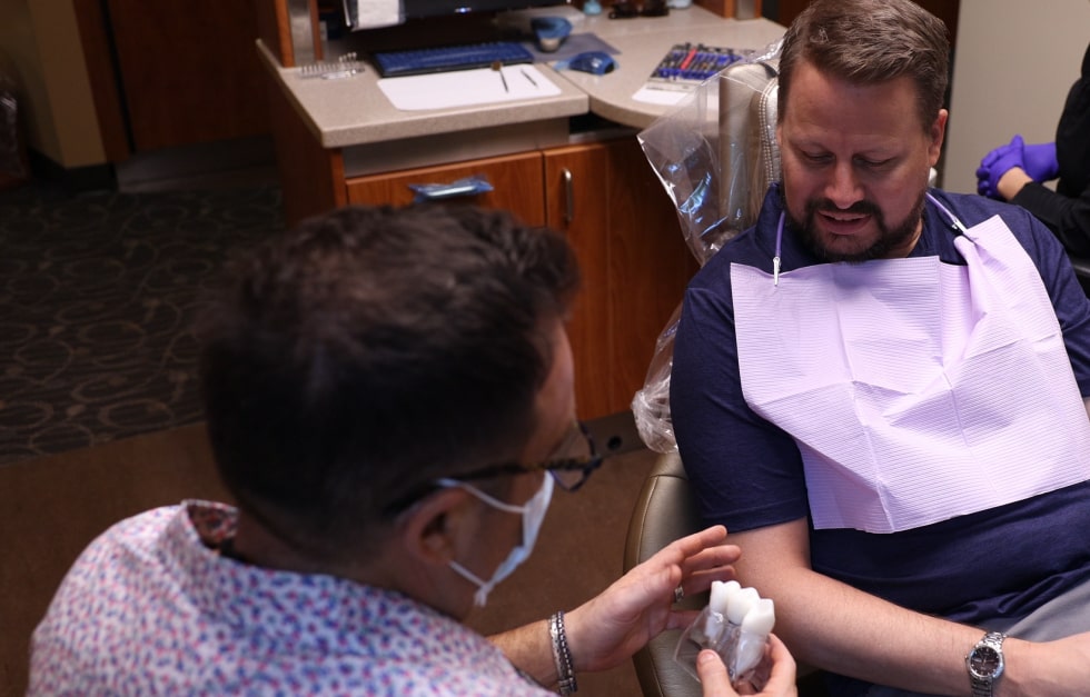 Dr. Ron Sherman and his dental assistant showcasing a dental implant prototype to a happy patient
