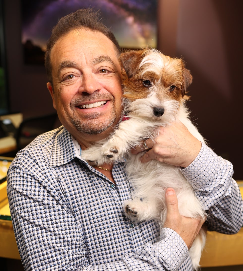 Dr. Ron cuddling his puppy at the First Impressions Dental Care dental office while smiling