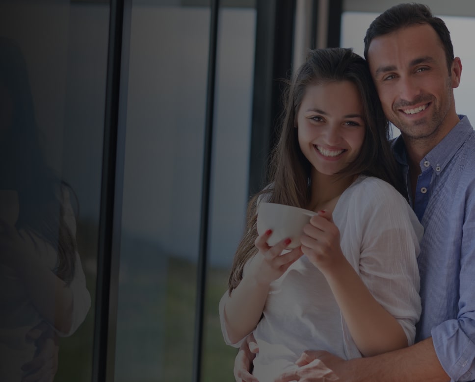 A couple is hugging with a coffee cup in women's hands, both smiling