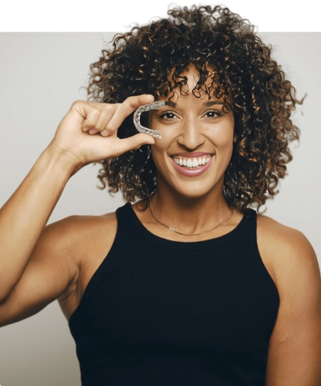 A woman is holding Invisalign and smiling