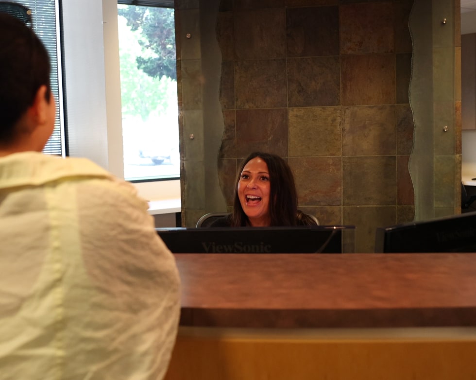 Front desk receptionist warmly welcoming a new patient with a friendly smile